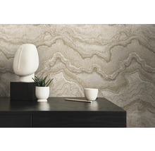 Dekoratives Arrangement mit Vliestapete in Marmoroptik, Skulptur, Pflanze und Schale auf einem Tisch