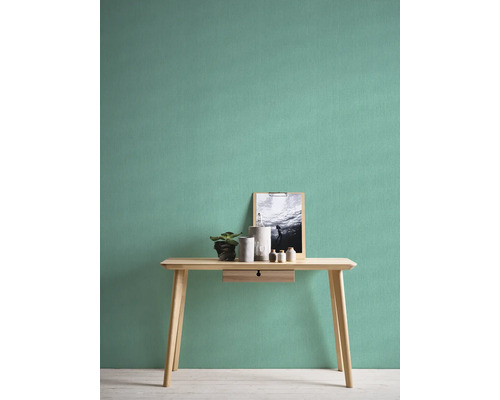 Helles Zimmer mit Uni-Tapete, Tisch, Pflanze und Dekorationsartikeln.