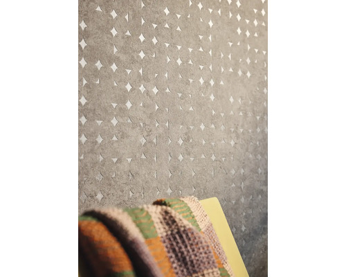 Papier peint gris avec motif de cercles et découpes en étoile sur un mur.