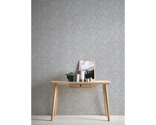 Scène avec un bureau en bois devant un papier peint gris à motifs.