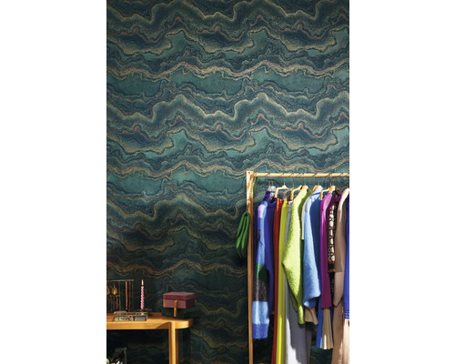 Ambiance d''intérieur avec un papier peint intissé vert à motif ondulé, un portant à vêtements et des accessoires