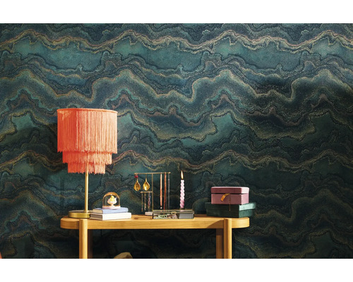 Scène avec papier peint à motifs, table et objets de décoration tels que lampe, présentoir à bijoux et bougie