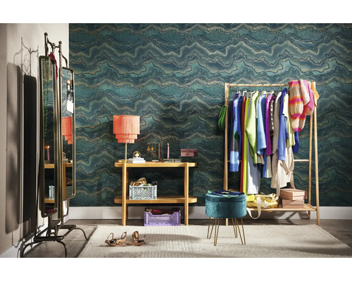 Exemple d''aménagement d''un dressing avec portant à vêtements, miroir, console, lampe, tabouret et papier peint à motifs.