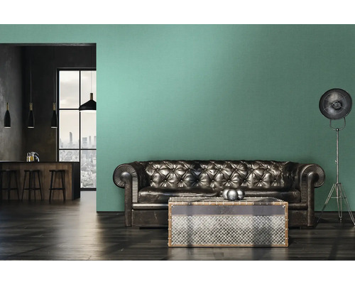 Wohnzimmer mit Ledersofa, Couchtisch und Stehlampe vor einer Wand mit grüner Tapete