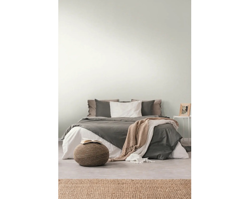 Schlafzimmer mit Bett, Nachttisch, Hocker und Teppich