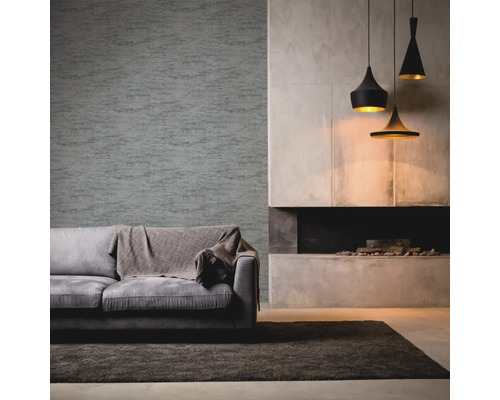 Salon avec canapé gris, couverture, papier peint à motifs, cheminée et suspensions