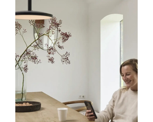 Salle à manger avec table, suspension, miroir et vase de fleurs