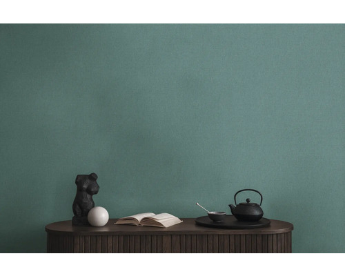 Detailaufnahme einer grünen Strukturtapete über einem Tisch mit Dekorationen.