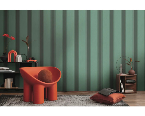 Gestuftes Wohnzimmer mit gemusterter Tapete, Sessel, Teppich und Beistelltisch.