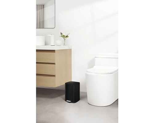 Salle de bains avec toilettes, lavabo et poubelle à pédale noire