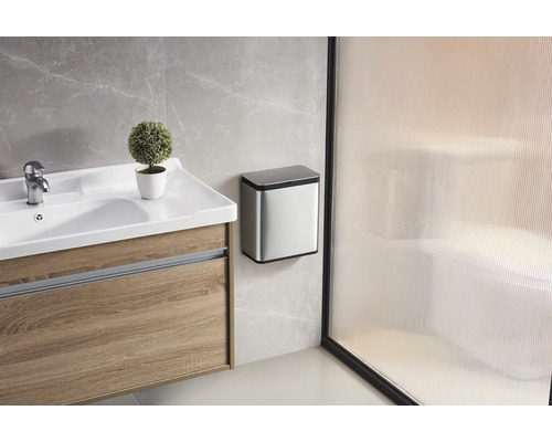 Badezimmer mit Waschtisch, Armatur, Dekoration und Abfalleimer an der Wand