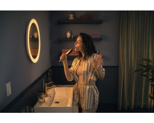 Femme chantant avec une brosse à cheveux dans une salle de bain avec miroir et lavabo