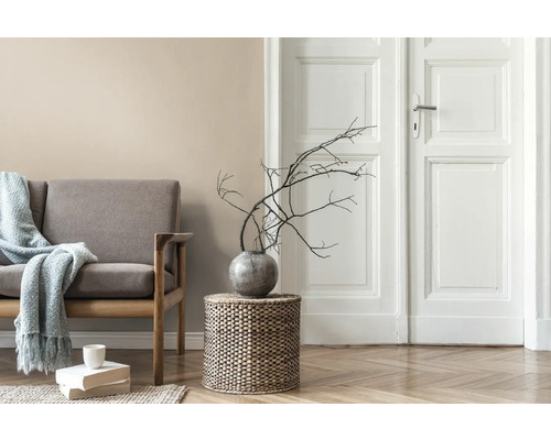 Wohnzimmer mit Sofa, Beistelltisch aus Korbgeflecht, Vase mit Ästen und Holztür