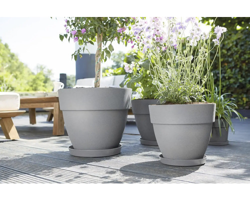 Blumenkübel aus Kunststoff mit Pflanzen auf einer Holzterrasse