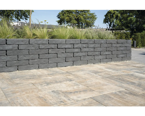 Mauer aus grauen Mauersteinen und Pflastersteinen im Garten