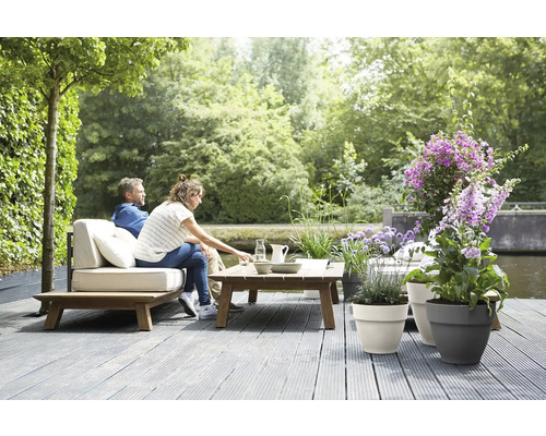 Scène extérieure avec couple sur mobilier de jardin, plancher en bois et pots de fleurs plantés