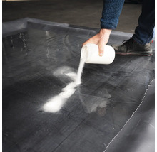 Une personne verse une poudre blanche sur une feuille noire.