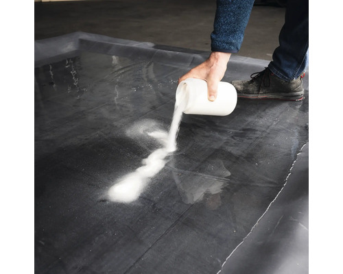 Une personne verse une poudre blanche sur une feuille noire.