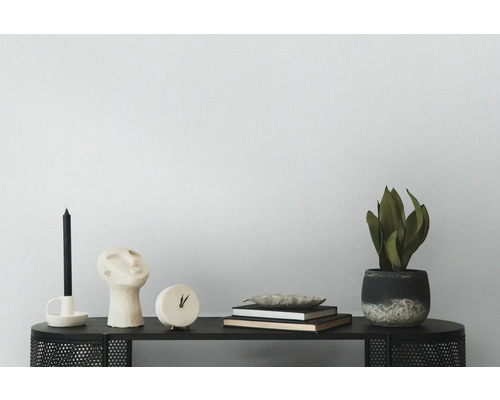 Dekorative Szene mit Kerze, Skulptur, Uhr, Büchern, Schale und Topfpflanze auf einem schwarzen Tisch.