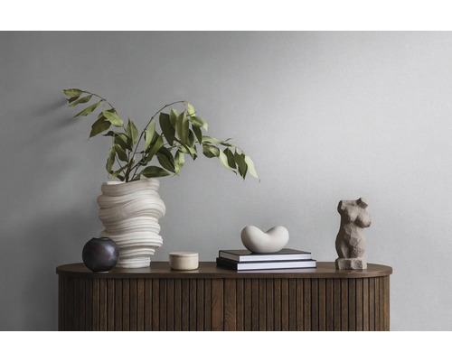 Dekoratives Stillleben mit Vase, Büchern und Skulpturen auf einem Holzschrank