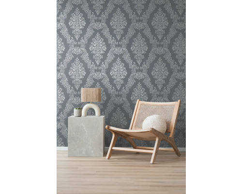 Raumansicht mit gemusterter Tapete, Sessel und Beistelltisch