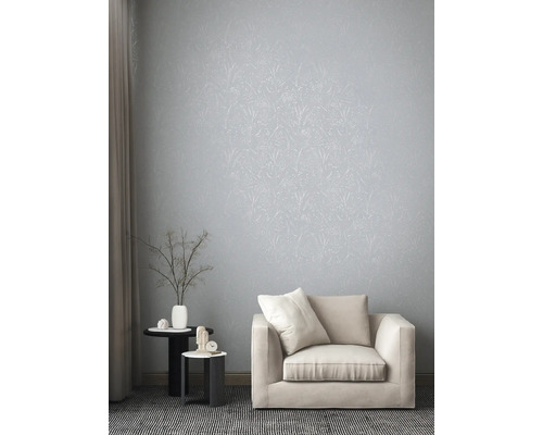 Helles Wohnzimmer mit floral gemusterter Tapete, Sessel und Beistelltischen.