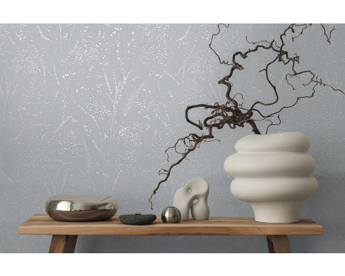 Dekoratives Interieur mit floral gemusterter Tapete und verschiedenen Objekten auf einem Holzregal