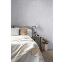 Chambre avec lit, table de chevet, lampe et papier peint à motifs végétaux