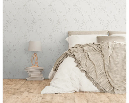 Schlafzimmer mit floraler Tapete, Bett und Lampe auf einem Bücherstapel