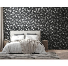 Chambre avec lit devant un papier peint foncé à motifs de feuilles
