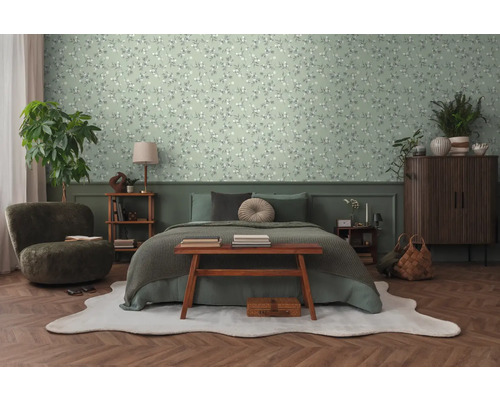 Schlafzimmer mit Bett, Sessel, Kommode und Blumentapete.