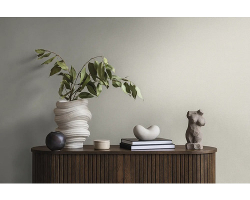 Dekoratives Sideboard mit Büchern, Statuen und Vase mit Grünpflanze.