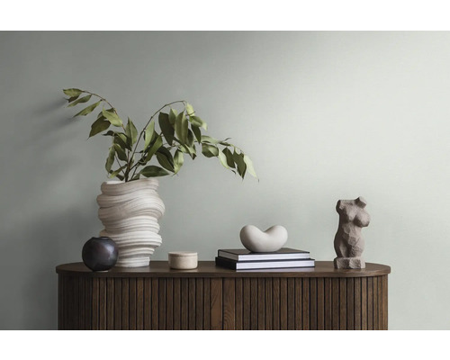 Dekoratives Arrangement mit Vase, Skulpturen und Büchern auf einem Holzschrank.