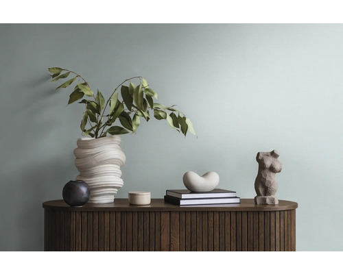 Dekoratives Arrangement auf einem Holzschrank mit Vase, Pflanze, Büchern und Skulpturen.