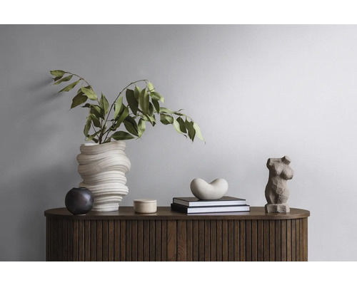 Dekoratives Arrangement auf einem Holzschrank mit Vase, Pflanzen, Büchern und Skulpturen.
