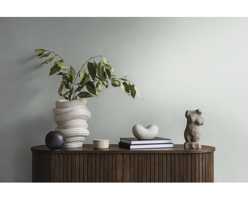 Dekoratives Arrangement auf einer Kommode mit Blumenvase, Büchern und Skulpturen.