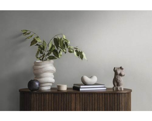Dekoratives Stillleben mit Blumenvase, Büchern und Skulpturen auf einem Holzschrank