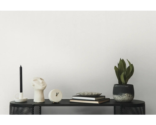 Arrangement décoratif avec bougie, sculpture, horloge, livres et plante en pot sur une étagère noire