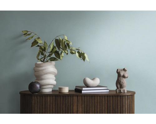 Dekoratives Interieur mit Vase, Skulpturen und Büchern auf einem Holzschrank.