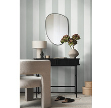 Intérieur décoratif avec miroir, table et chaise devant un papier peint rayé