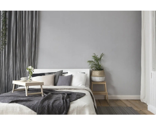 Schlafzimmer mit Bett, Nachttisch, Zimmerpflanze und Vorhängen