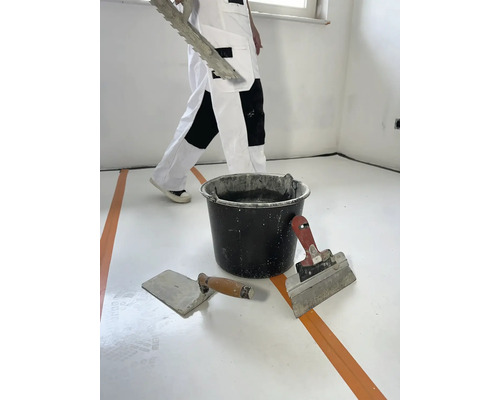 Rénovation de pièce avec spatule, lisseuse et seau de mortier