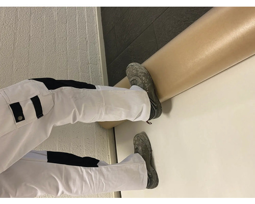 Peintre en vêtements de travail et peinture sur un mur