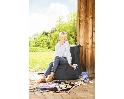 Frau sitzt auf einem grauen Sitzsack im Garten