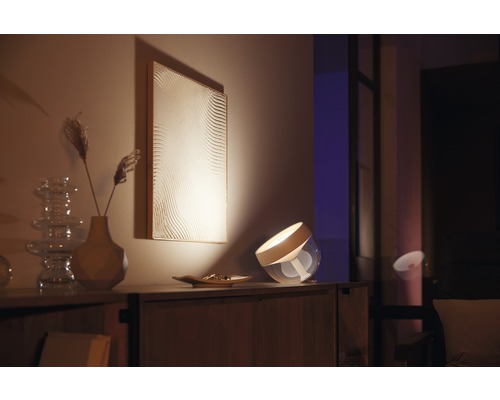 Dekorative Tischleuchte auf einem Holzschrank mit Kunstwerk im Hintergrund