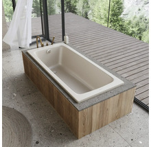 Beige Badewanne mit Holzverkleidung und Armatur in einem hellen Badezimmer