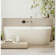 Freistehende Badewanne mit Armatur und Handbrause in einem hellen Badezimmer.