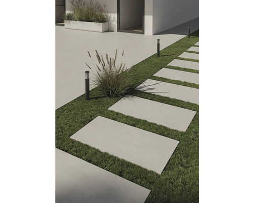 Außenbereich mit rechteckigen Terrassenplatten auf Grasfläche und dezenten Außenleuchten