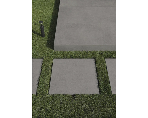 Szene mit grauen Terrassenplatten und Rasenflächen, ergänzt durch eine Aussenleuchte.