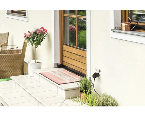 Eingangsbereich eines Hauses mit Haustür, Treppe, Pflanzen und Außensteckdose